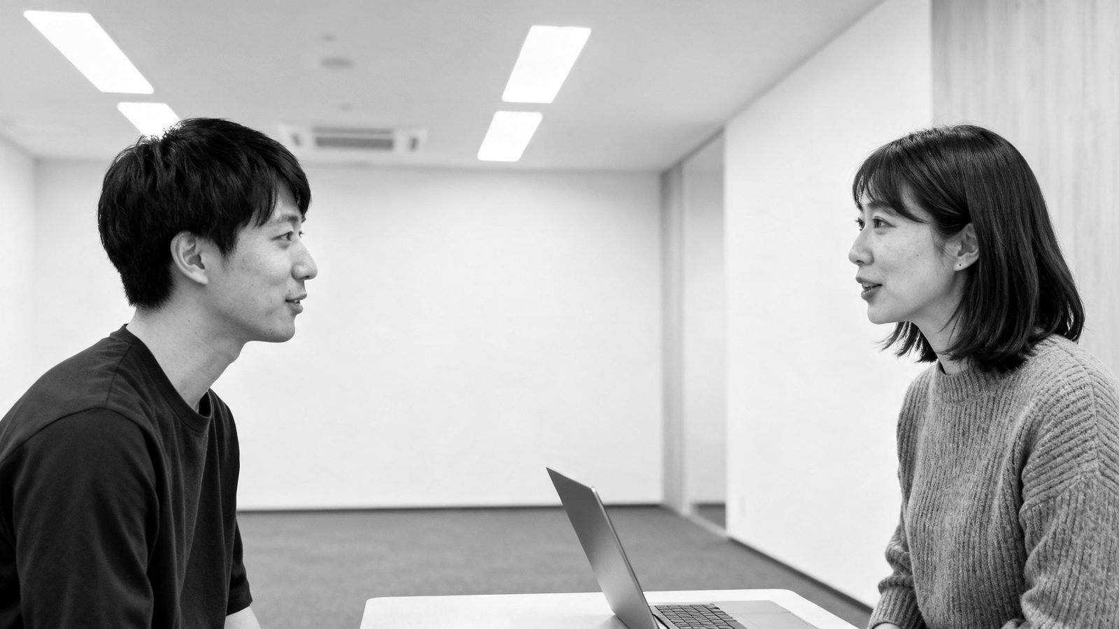 問い合わせへの連絡の順番を打ち合わせる2人(イメージ)