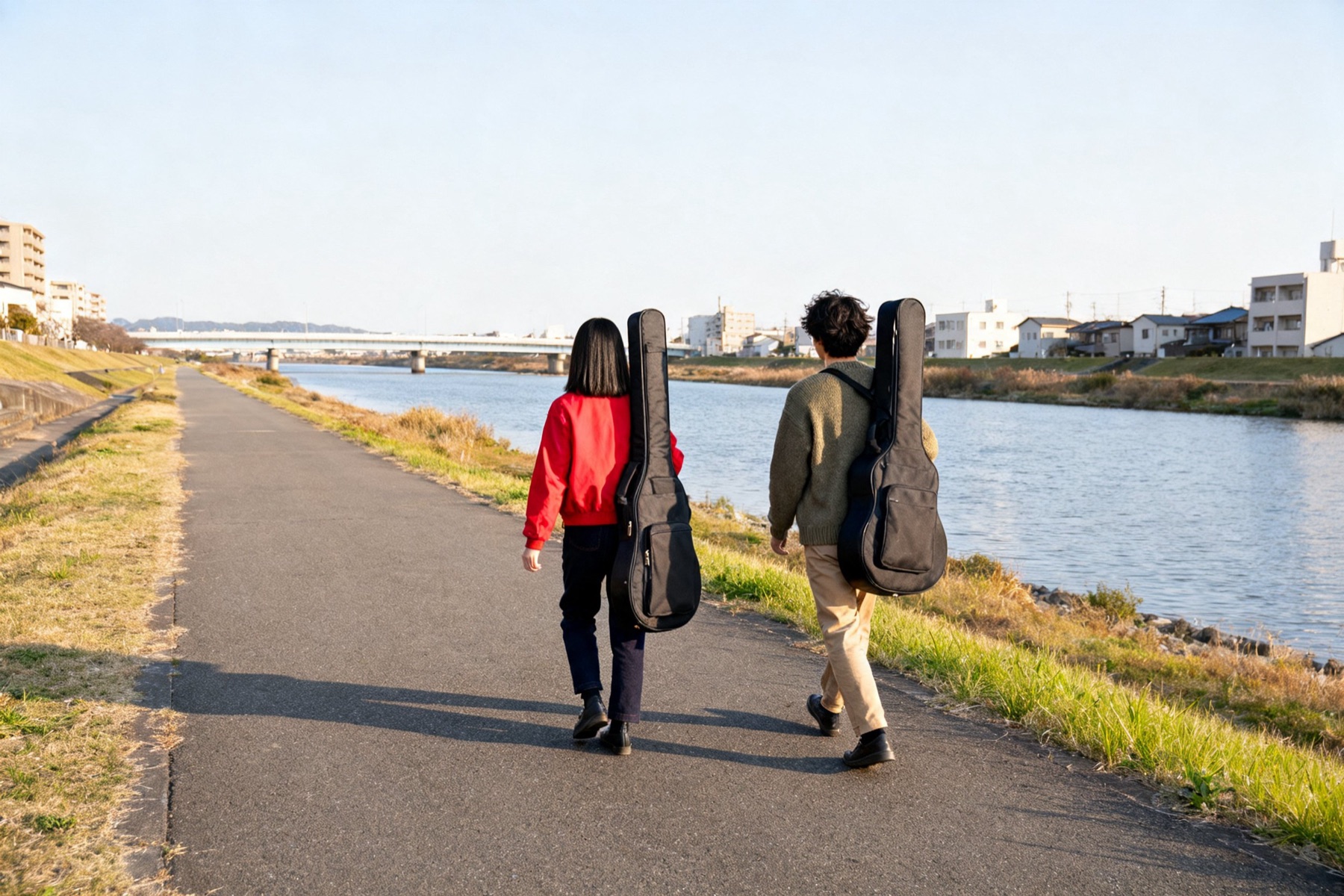 楽器ケースを背負って川沿いの道を歩く2人（イメージ）