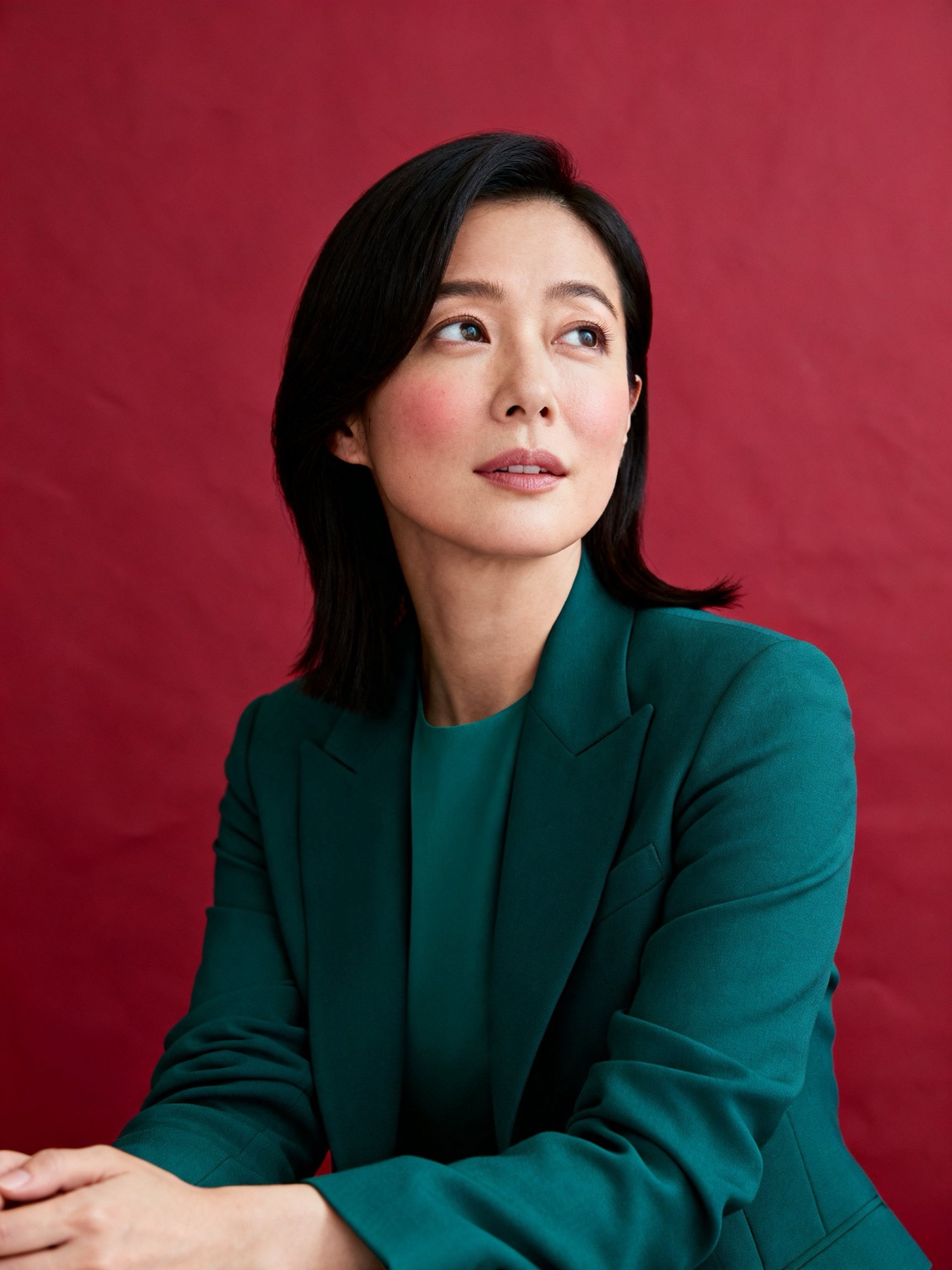 プロデューサー・40代女性。腕を組んで斜め上を見る（イメージ・架空の人物）