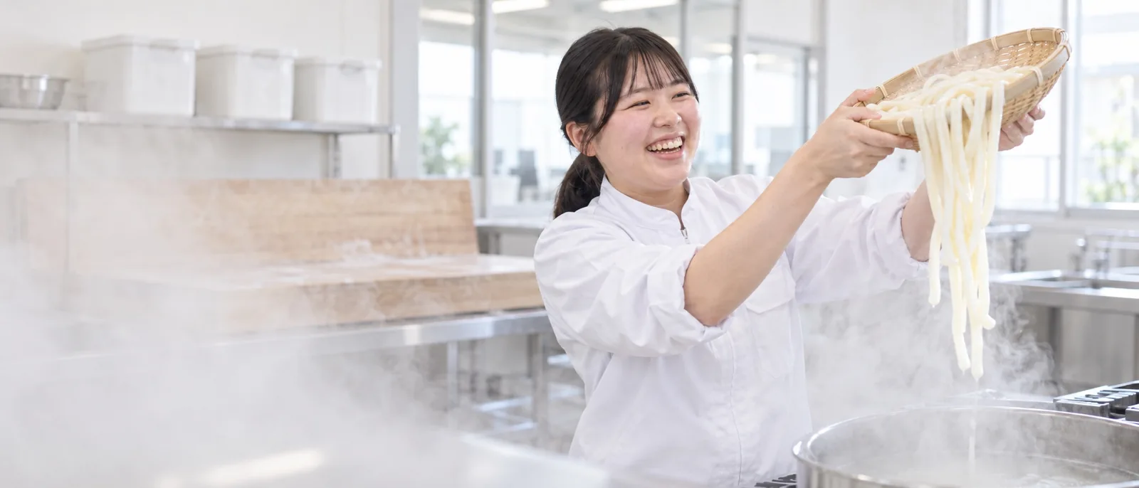 ゆでたての麺をざるで持ち上げる社員