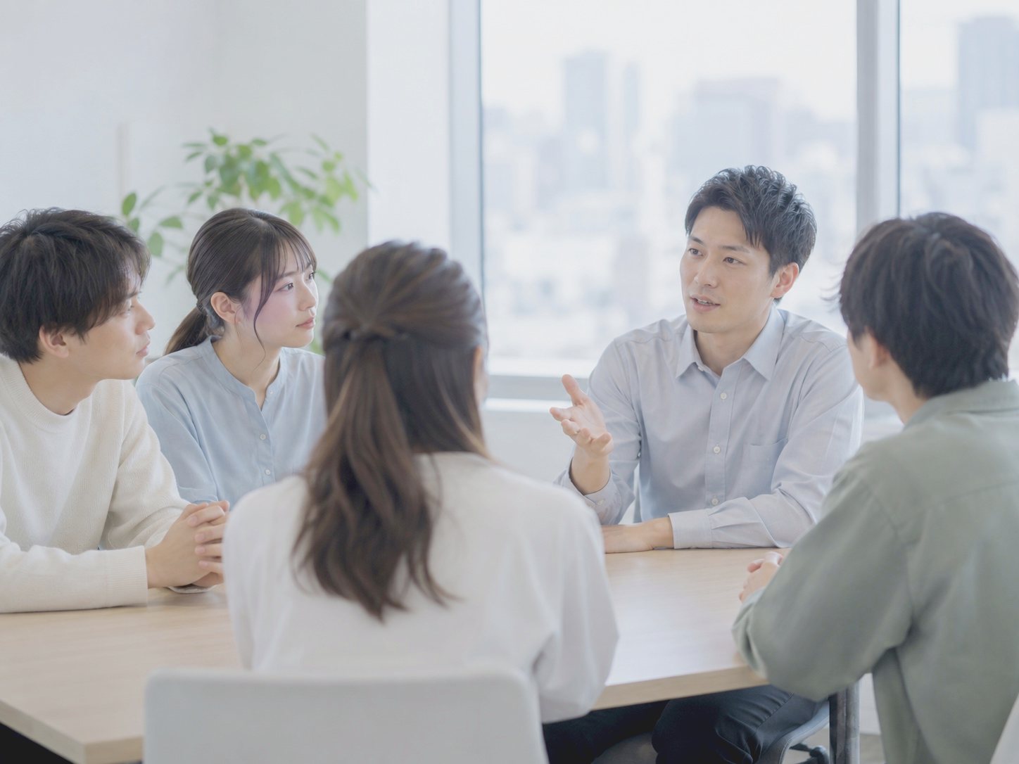 会議室で先輩の話を聞く新人たち