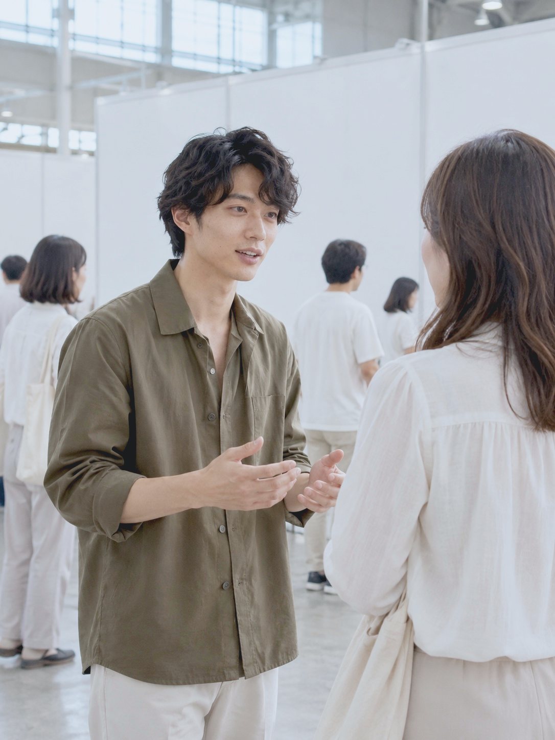 展示会の当日、ブースの前でお客さまと話す R.N